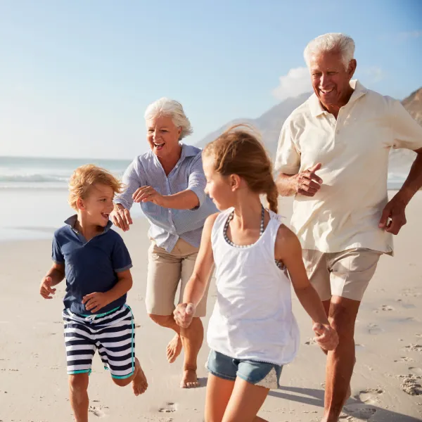 Healthy, active, Grandparents running and playing with kids on a beach