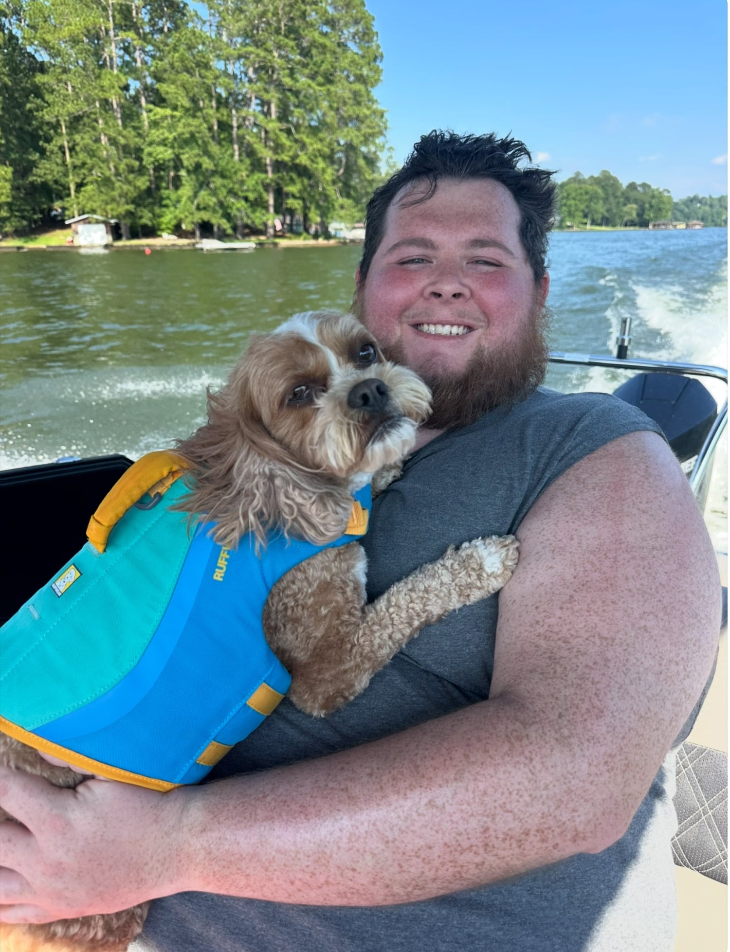 Picture of big man and little dog in boat on lake
