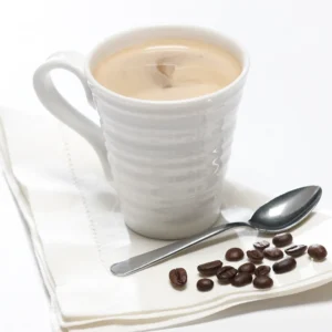 picture of a cup of creamy cappuccino with spoon and coffee beans lying beside it